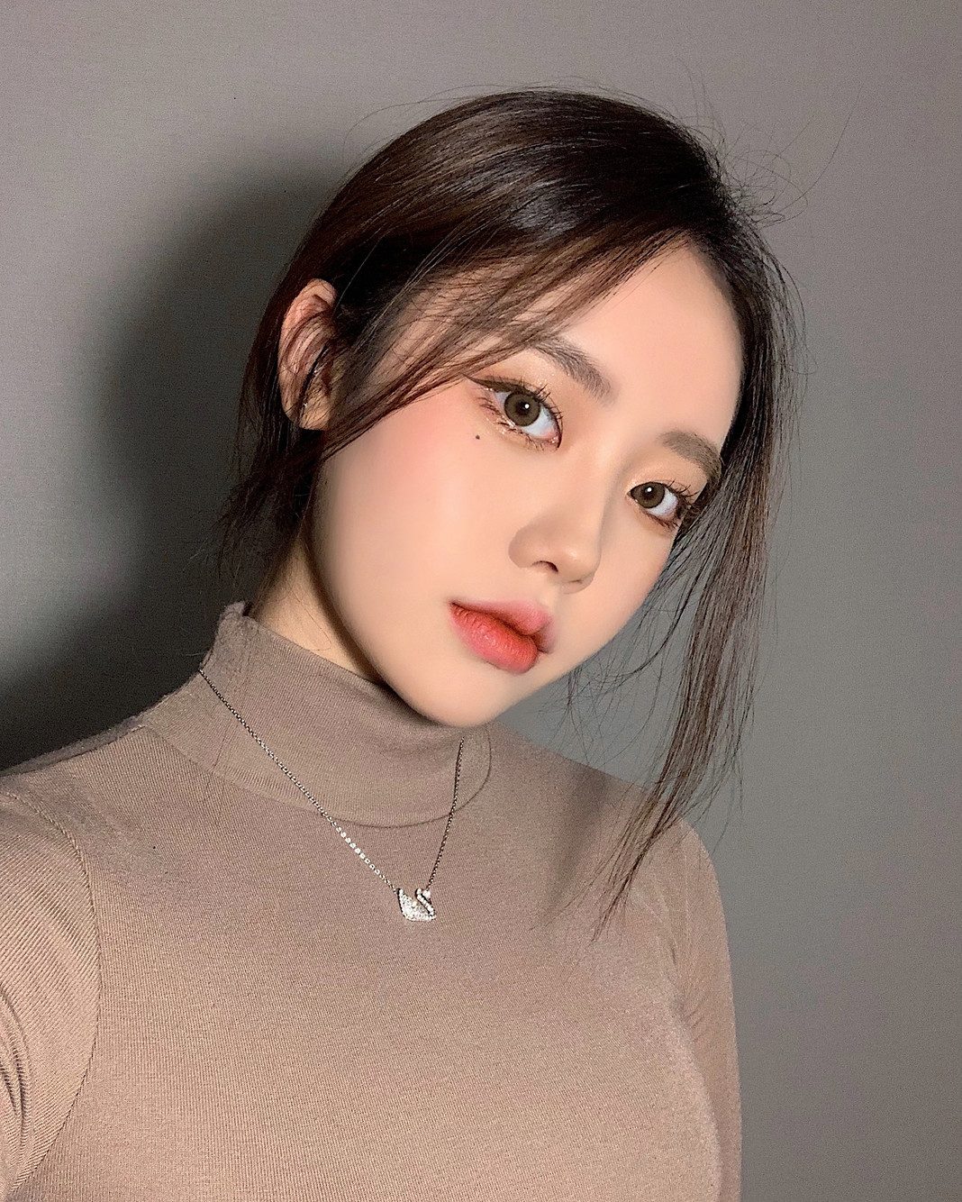 베이지 니트를 입고 카메라를 바라보는 여성 셀피